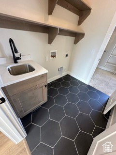 Laundry area featuring hookup for a washing machine, dark tile patterned flooring, laundry area, electric dryer hookup, and a sink