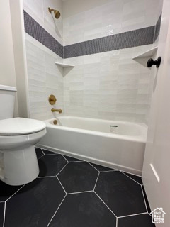 Full bathroom featuring toilet, washtub / shower combination, and tile patterned floors