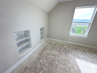 Additional living space featuring lofted ceiling, baseboards, and built in shelves