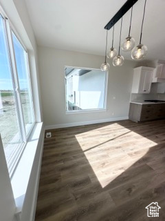 Unfurnished dining area with dark wood-style flooring and baseboards