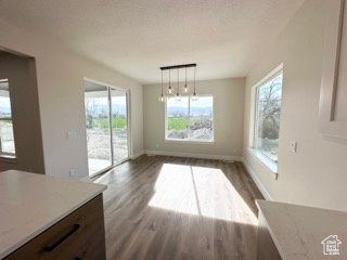 Unfurnished dining area with dark wood-style floors and baseboards