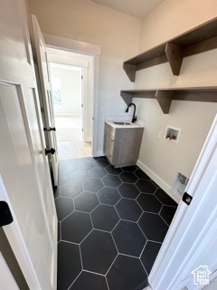 Laundry room featuring a sink, laundry area, hookup for a washing machine, baseboards, and dark tile patterned floors