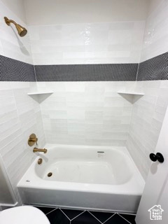 Full bathroom featuring tile patterned floors, toilet, and bathtub / shower combination