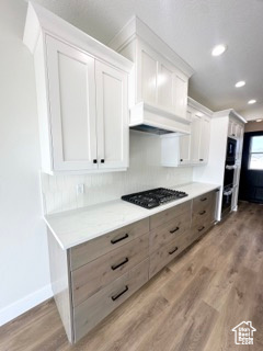 Kitchen featuring light wood-style flooring, light countertops, gas stovetop, and white cabinets