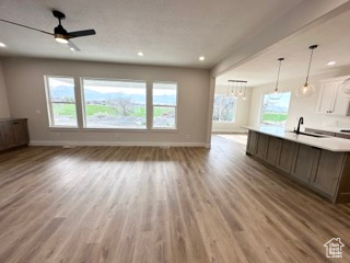 Unfurnished living room with a sink, plenty of natural light, light wood-style flooring, and baseboards