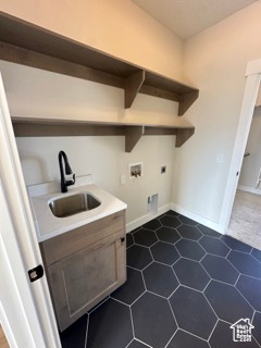 Washroom featuring hookup for a washing machine, laundry area, dark tile patterned floors, hookup for an electric dryer, and a sink