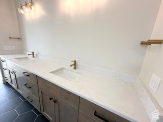 Bathroom featuring tile patterned flooring, double vanity, and a sink
