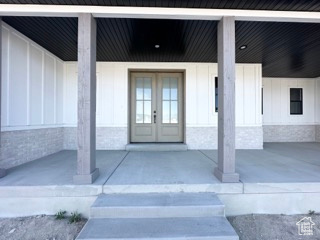 Entrance to property featuring board and batten siding, a porch, french doors, and an attached carport