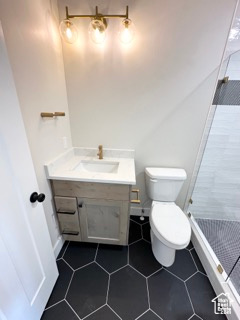 Full bathroom with tile patterned floors, a shower stall, toilet, vanity, and baseboards