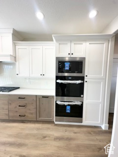 Kitchen featuring appliances with stainless steel finishes, light wood-type flooring, and white cabinets