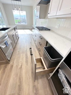Kitchen with light wood-type flooring, light countertops, dishwasher, and stainless steel gas stovetop