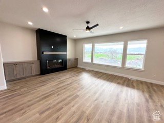 Unfurnished living room with recessed lighting, a ceiling fan, wood finished floors, and baseboards