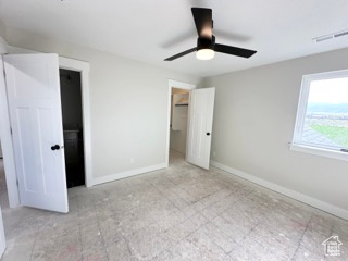 Unfurnished bedroom featuring visible vents, a walk in closet, a ceiling fan, and baseboards