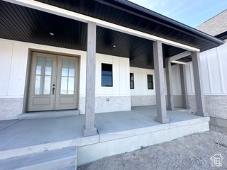Doorway to property with covered porch, french doors, and board and batten siding