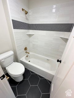 Bathroom featuring toilet, shower / bathtub combination, and tile patterned flooring
