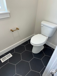 Bathroom featuring visible vents, toilet, and baseboards