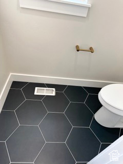 Details featuring baseboards, visible vents, and toilet