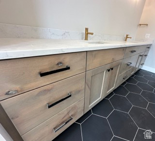 Bathroom featuring double vanity, a sink, tile patterned flooring, and baseboards