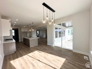 Kitchen featuring light countertops, baseboards, dark wood-style flooring, open floor plan, and an island with sink
