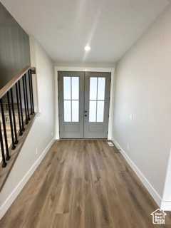 Doorway featuring baseboards, stairway, wood finished floors, and french doors