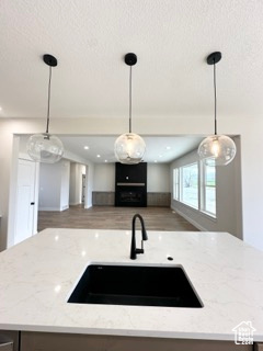 Kitchen featuring open floor plan, light stone countertops, a textured ceiling, and a sink