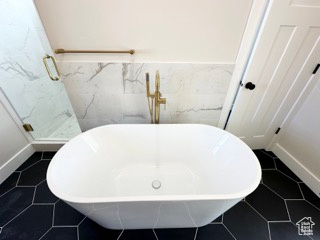 Bathroom with tile patterned floors, a shower stall, a freestanding bath, and wainscoting