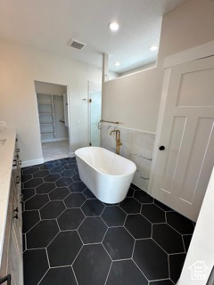 Bathroom featuring a freestanding bath, a shower stall, tile walls, vanity, and visible vents
