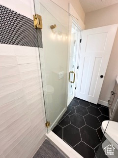 Bathroom featuring toilet, a shower stall, tile patterned flooring, and baseboards