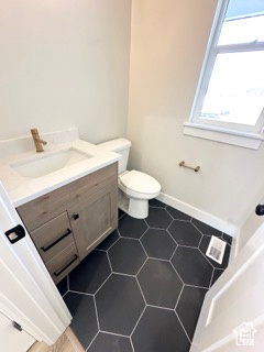Bathroom featuring toilet, tile patterned flooring, vanity, and baseboards