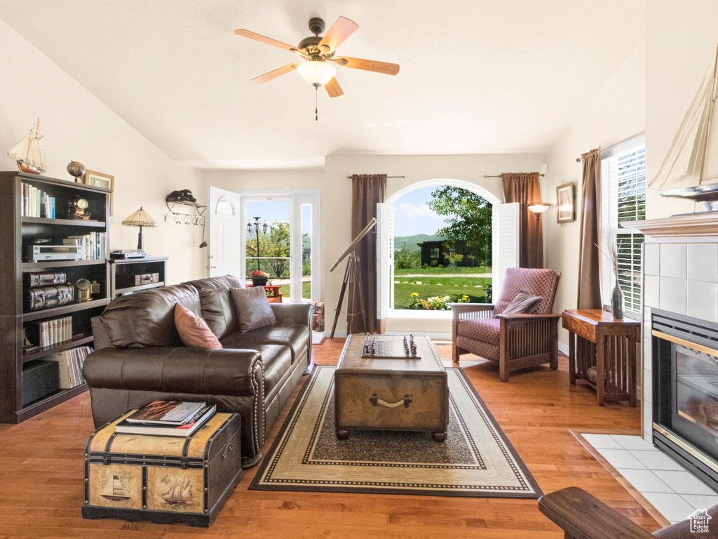 Living room featuring a tile fireplace, ceiling fan, wood finished floors, and plenty of natural light