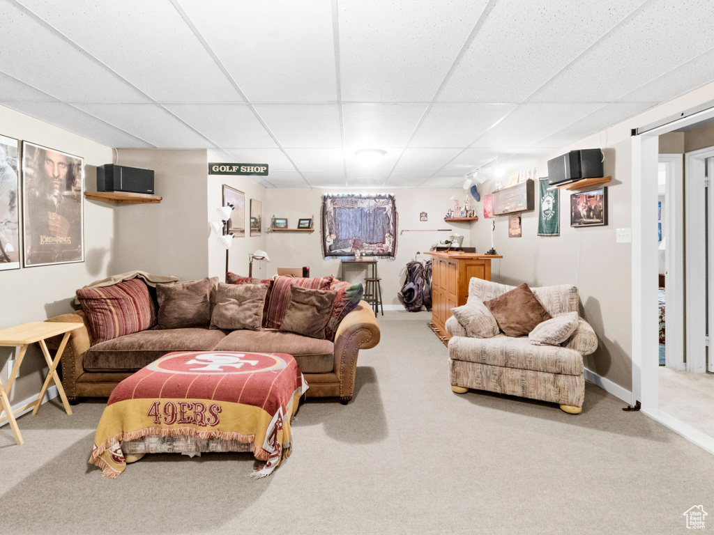 Living room featuring baseboards, carpet floors, a drop ceiling, and indoor bar