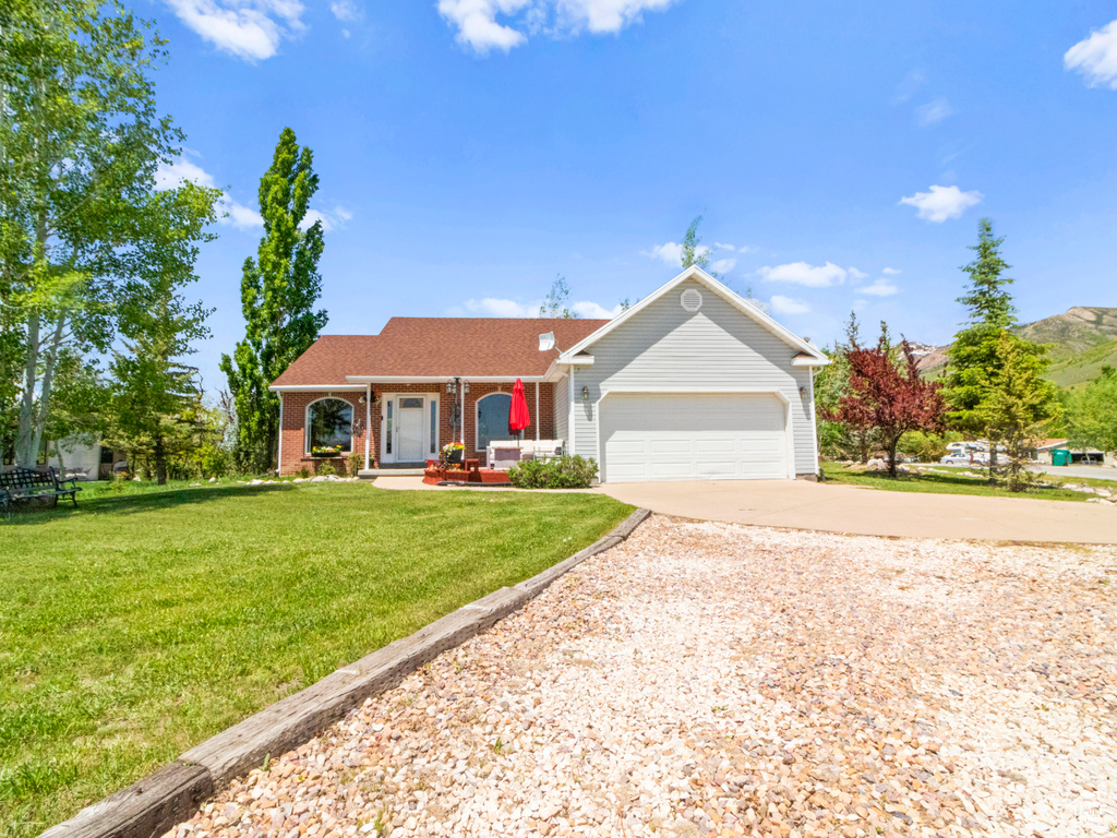 Ranch-style house featuring an attached garage, a front lawn, driveway, and covered porch
