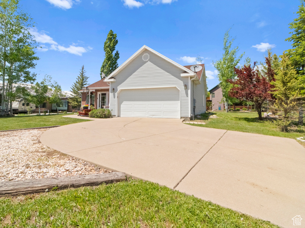 View of front facade with a garage, a front yard, and concrete driveway