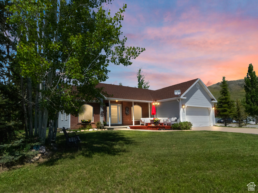 Ranch-style home with concrete driveway, an attached garage, a porch, a yard, and brick siding