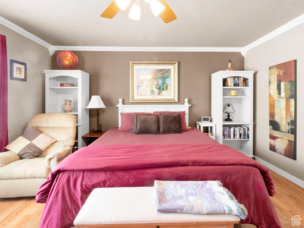 Bedroom featuring baseboards, a ceiling fan, wood finished floors, and ornamental molding