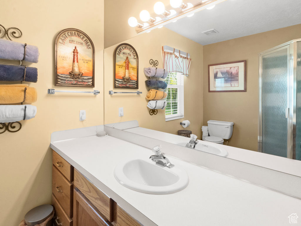 Bathroom featuring a stall shower, visible vents, vanity, and toilet