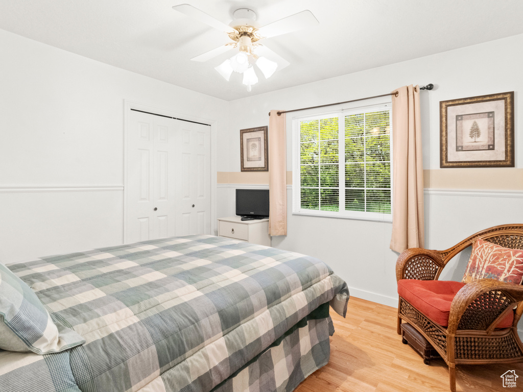 Bedroom featuring a ceiling fan, baseboards, light wood-style floors, and a closet