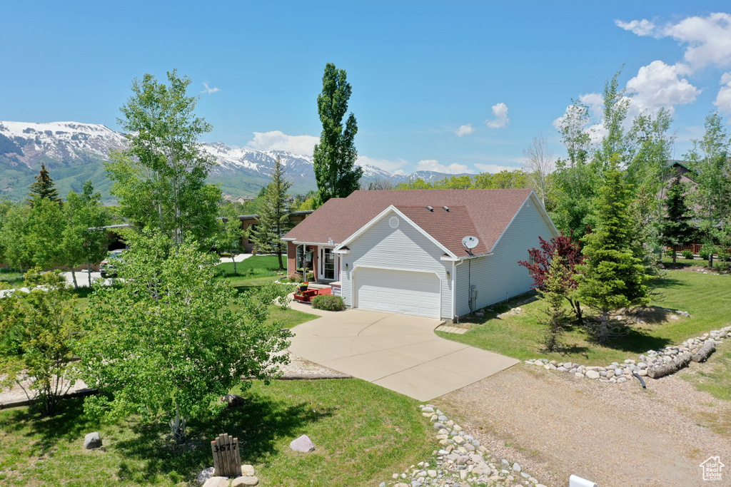 Ranch-style home with concrete driveway, an attached garage, a mountain view, and a front lawn