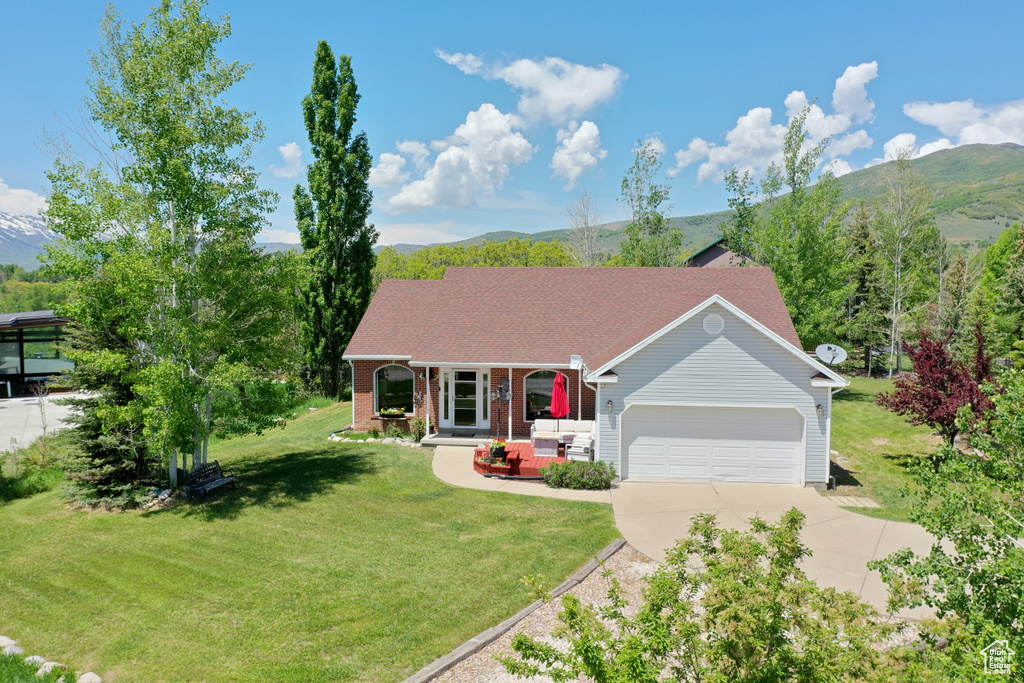 Single story home featuring an attached garage, driveway, a front yard, and a mountain view