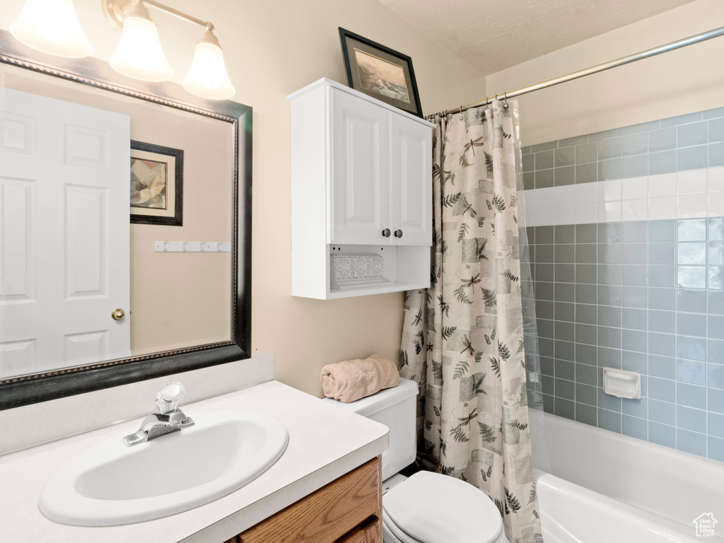 Bathroom featuring toilet, vanity, and shower / bath combo with shower curtain