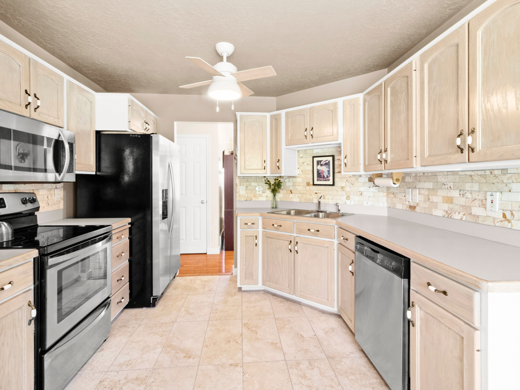 Kitchen featuring appliances with stainless steel finishes, light brown cabinets, and a ceiling fan