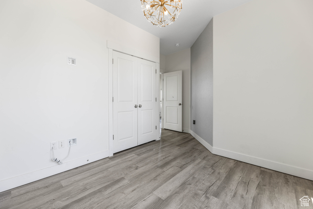 Spare room featuring wood finished floors, a chandelier, and baseboards