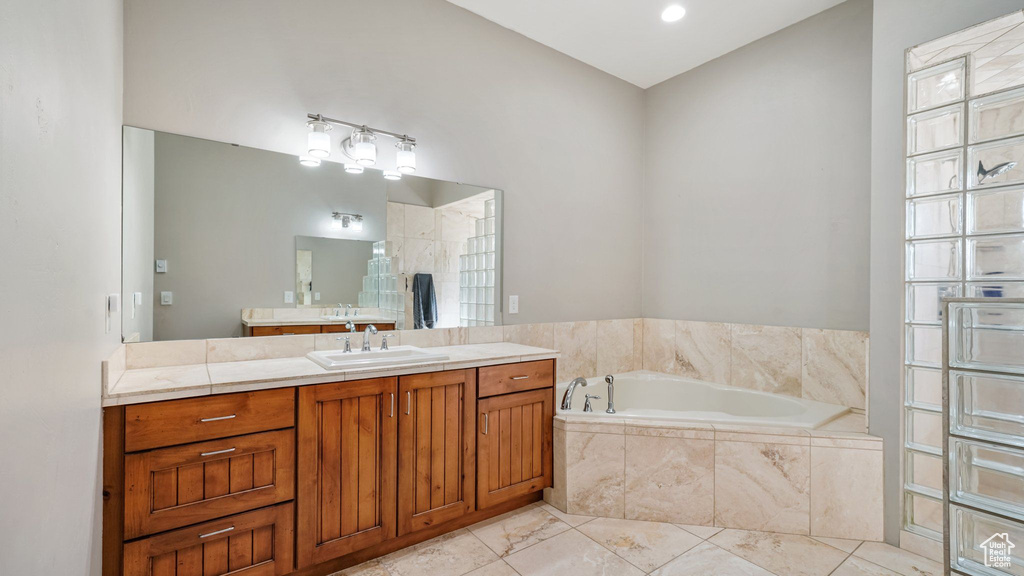 Bathroom featuring vanity, a garden tub, and marble finish flooring