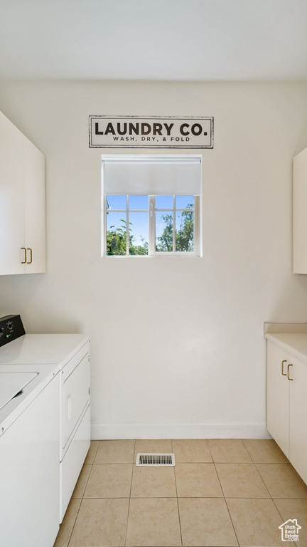 Washroom featuring cabinet space, separate washer and dryer, and light tile patterned flooring