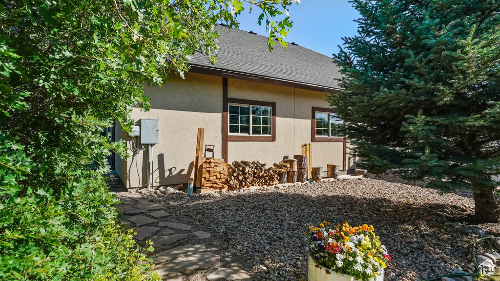 View of side of property featuring stucco siding and roof with shingles