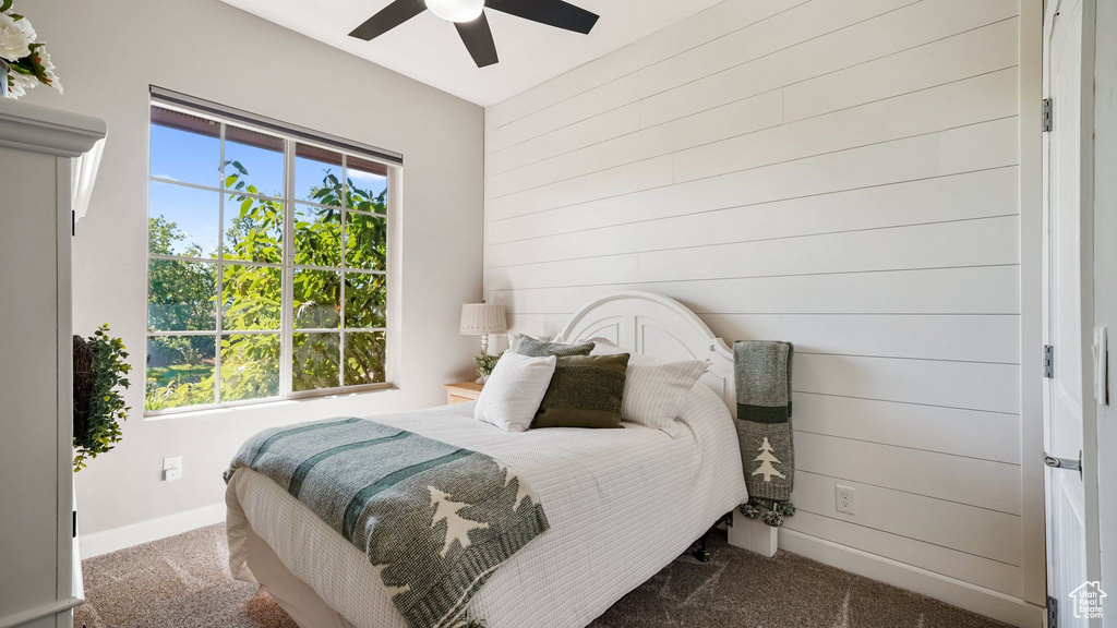 Carpeted bedroom with wooden walls and a ceiling fan