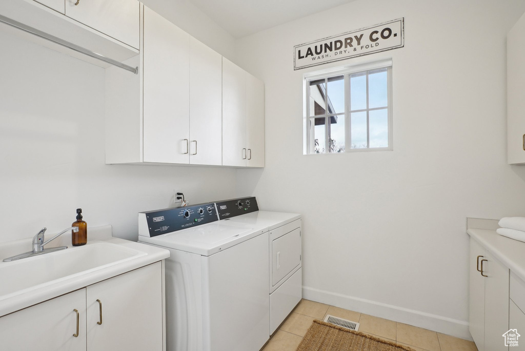 Laundry area featuring cabinet space, washer and clothes dryer, and light tile patterned floors
