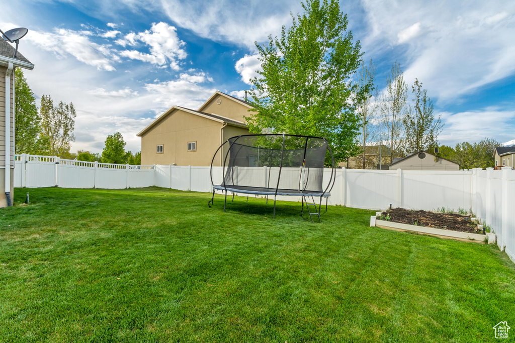 View of yard featuring a fenced backyard and a trampoline