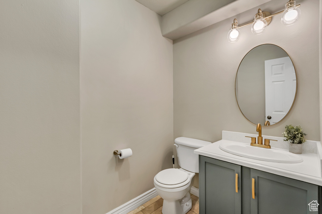 Half bathroom with baseboards, vanity, and toilet