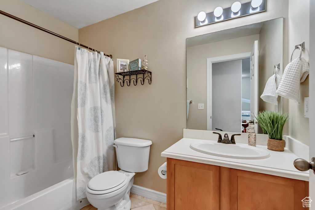 Bathroom featuring shower / bath combination with curtain, toilet, vanity, and tile patterned floors